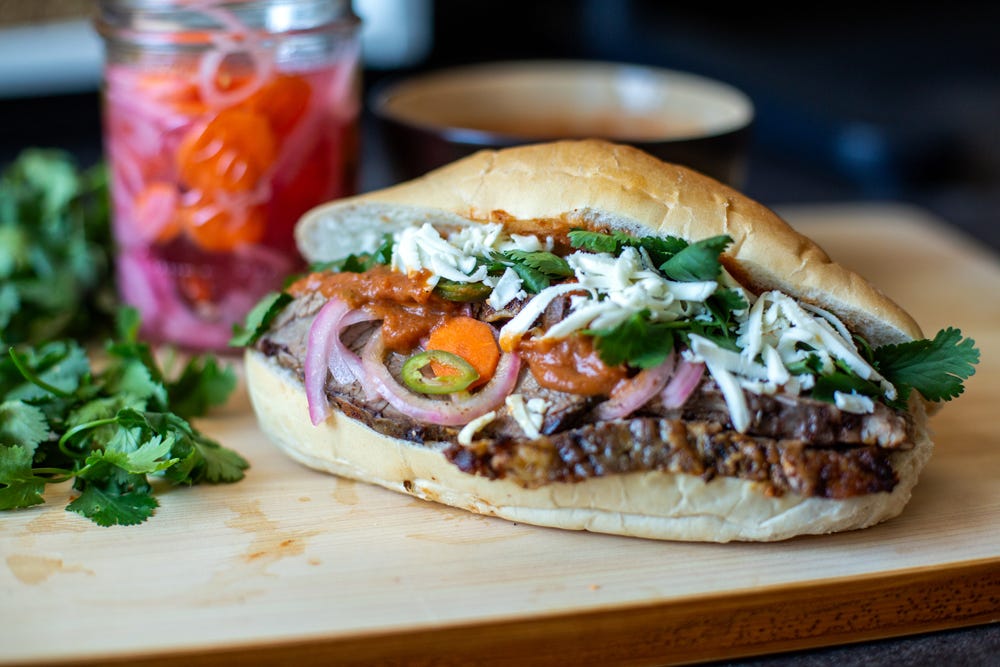 Close up of an overflowing brisket torta sandwich.