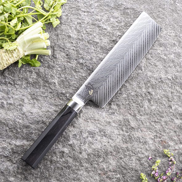 Nakiri knife in use slicing vegetables on a cutting board.