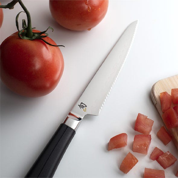 Utility knife styled with sliced citrus on a light surface.