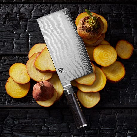 Shun Classic vegetable cleaver styled with golden beets on a dark textured surface.