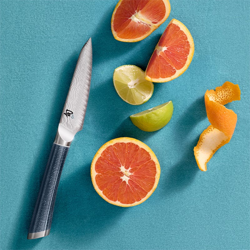 Shun Shiranami 4-inch paring knife with citrus slices on blue background