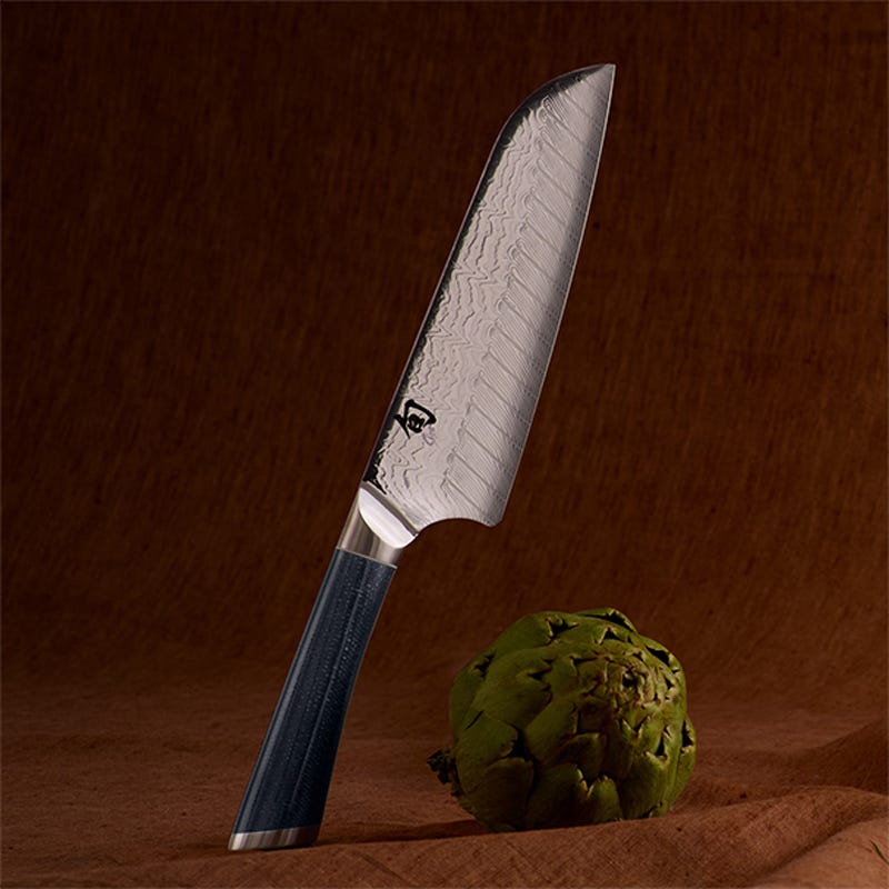 Shun Shiranami 7-inch santoku knife with Damascus blade beside artichoke on wooden surface