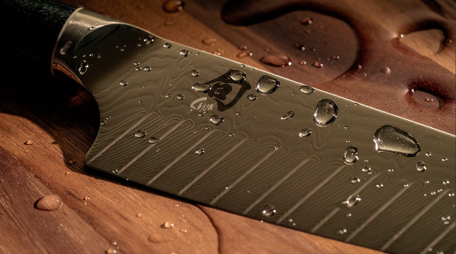 Close-up of Shun Shiranami Damascus blade with water droplets on wooden cutting board